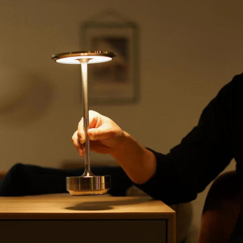 Elegante kabellose LED-Tischlampe auf einem Holzregal, die einen gemütlichen Innenraum sanft beleuchtet