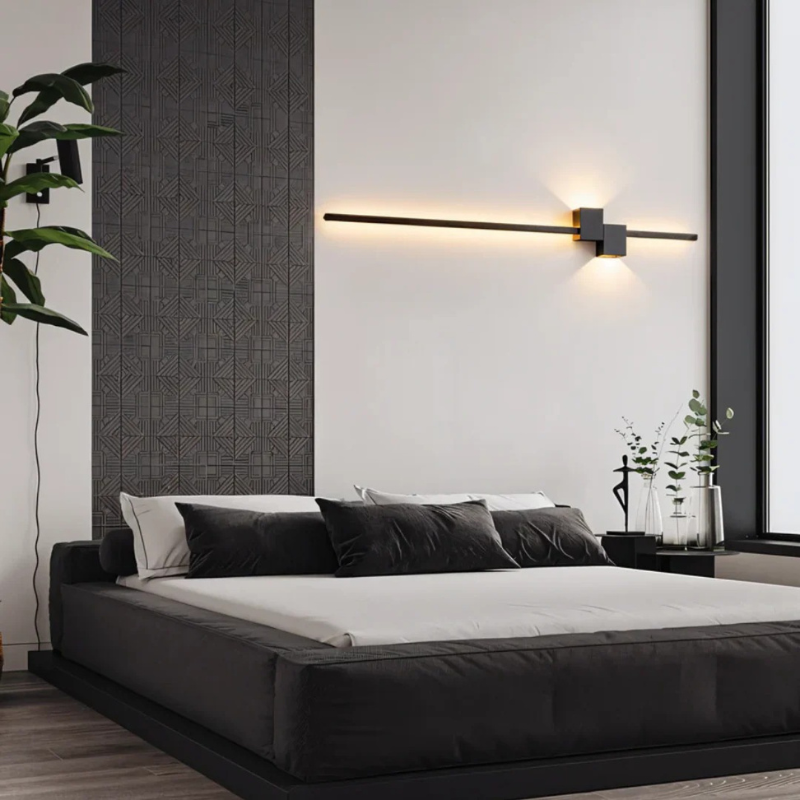 Moderne minimalistische LED-Wandleuchte in Schwarz, Weiß und Gold, die warmes weißes Licht für elegante Innenräume spendet.